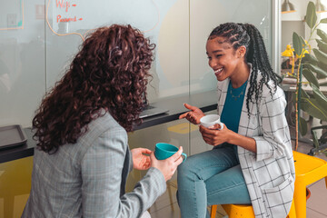 Cheerful black woman with cup of coffee at the office