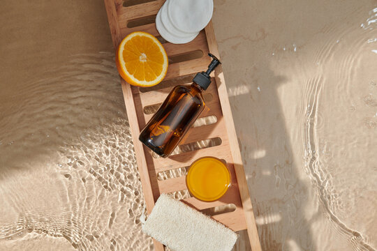 Wooden tray with accessories and fresh fruit on bathtub, closeup