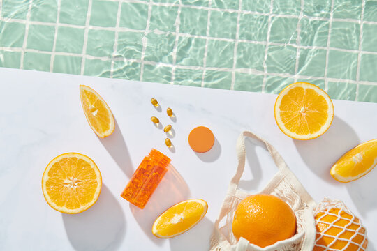 orange transparent vitamin bottle with citrus fruits and pills