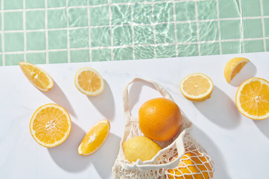 Ripe oranges in a white eco-cotton string bag near pool