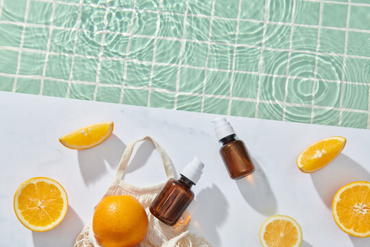 citrus fruit in skincare product and cut orange near swimming pool