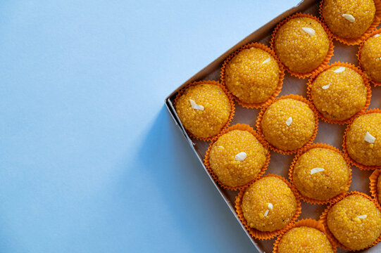 Laddu sweets kept in the box packing with pale blue background and copy space. Laddu or laddoo is spherical Indian sweet made of various ingredients and made during various Indian Hindu festivals.