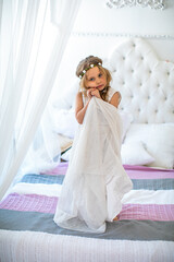 Beautiful girl in white dress standing on bed