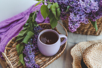 Cup of tea, straw hat and lilac basket, spring still life