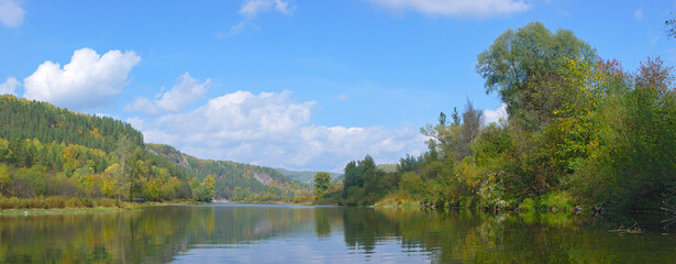 Amazing panorama of the river with rocks illuminated by the sun on a beautiful autumn day.