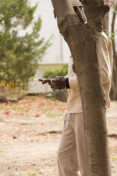 Man using smart phone behind the tree