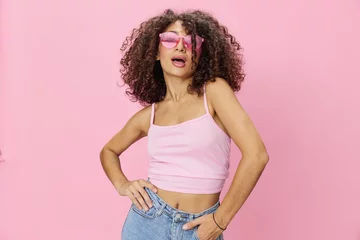 Keuken foto achterwand Graffiti collage Woman with curly afro hair with sunglasses model poses on a pink background in a pink T-shirt, free movement and dance, look into the camera, smile with teeth and happiness, copy space