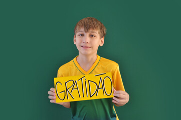 menino brasileiro segurando placa da gratidão 