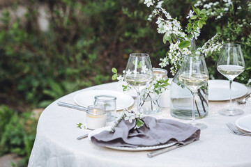 Romantic elegant luxury wedding table decor with white fresh spring blooming cherry apple tree flowers. Glass, candles, floral decoration for special marriage holiday event. No plastic zero waste