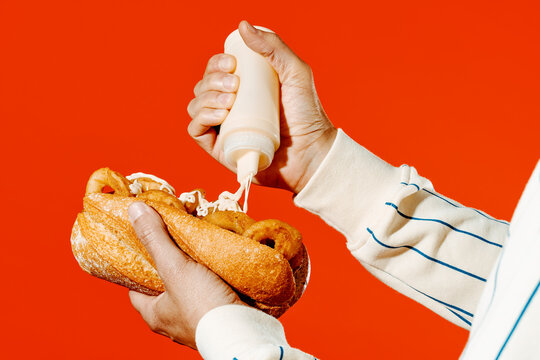 man puts some mayo in a spanish calamari sandwich