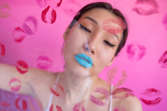 Woman with colorful makeup behind wall with kiss stains