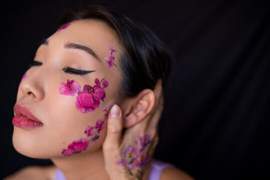 Young Asian lady with painted flowers on face in studio