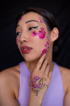 Young Asian lady with painted flowers on face in studio