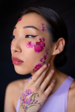 Young Asian lady with painted flowers on face in studio