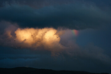 sunset after rain with rainbow and bright yellow cloud