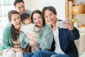 スマートフォンで自撮りをする三世代の家族