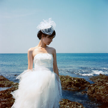 Girl in wedding dress standing by the sea