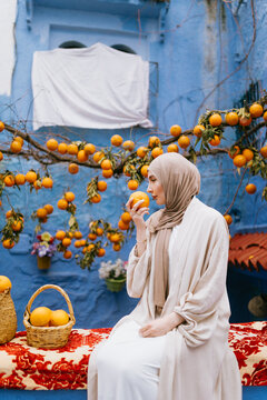 Muslim woman smelling an orange