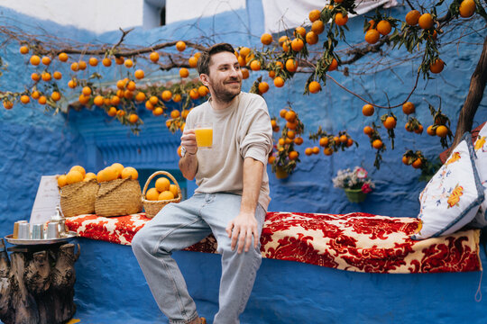 Smiley man holding orange juice glass