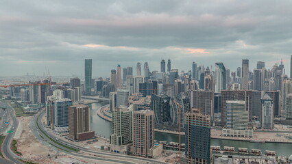 Naklejka na ściany i meble Skyline with modern architecture of Dubai business bay towers night to day timelapse. Aerial view