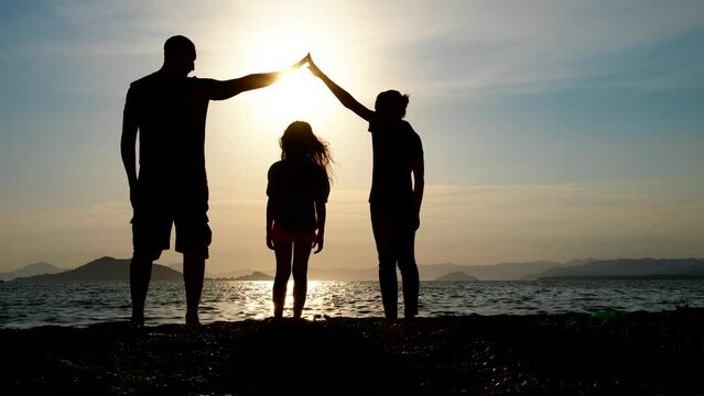 Parental protection. Silhouette of parents making a roof over the child with their hands.
