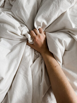 A hand clutching a white blanket