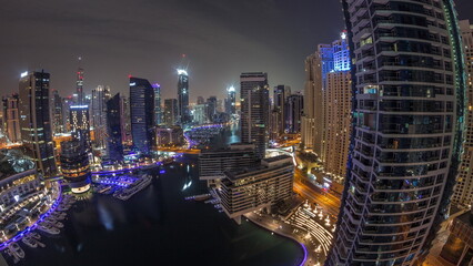 Fototapeta na wymiar Aerial view to Dubai marina skyscrapers around canal with floating boats all night timelapse