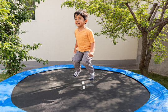 A Smiling Kid Playing On A Trampoline