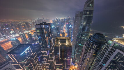 Fototapeta premium Skyline panoramic view of Dubai Marina showing canal surrounded by skyscrapers along shoreline all night timelapse. DUBAI, UAE