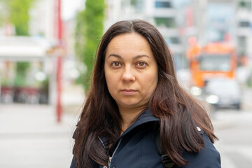 Fototapeta premium street portrait of a 40-45-year-old woman on a blurry urban background.