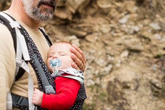 Father with sleeping newborn on baby carrier 