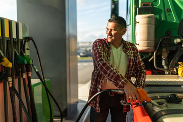 a truck driver fills his tank with fuel before continuing on his route, after a break at a gas...