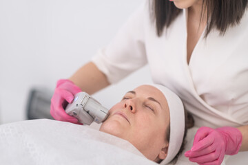 Obraz na płótnie Canvas close up beautician doctor hands with ultrasound laser face lifting using professional equipment 