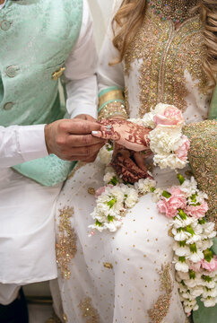 The groom puts a diamond ring on the bride's finger during an Indian wedding ceremony. Henna drawings in the form of Indian traditional patterns on the hands of the bride. Traditional Indian patterns