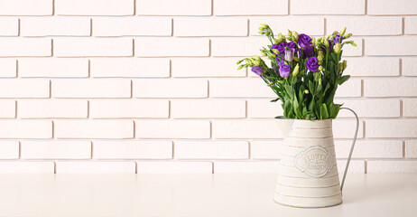 Vase with beautiful eustoma flowers on table near white brick wall. Banner for design