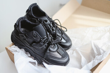 Unpacking women's shoes, stylish black sneakers in hands