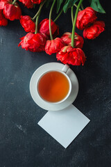 Greeting card with place for your text, cup of tea and spring flowers top view