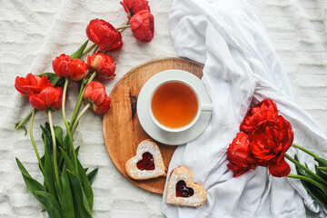 Tray with tasty breakfast, bouquet of peonies and gift for Valentine's Day on bed