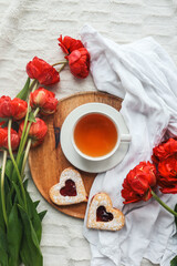 Tray with tasty breakfast, bouquet of peonies and gift for Valentine's Day on bed