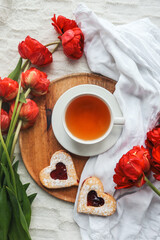 Tray with tasty breakfast, bouquet of peonies and gift for Valentine's Day on bed