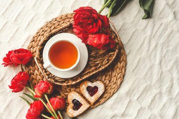 Tray with tasty breakfast, bouquet of peonies and gift for Valentine's Day on bed