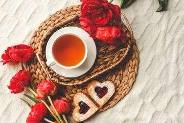 Tray with tasty breakfast, bouquet of peonies and gift for Valentine's Day on bed