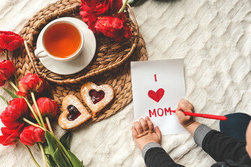 The child draws a card for mother's day for mom, a festive concert