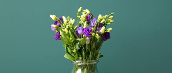 Vase with bouquet of eustoma flowers on green background