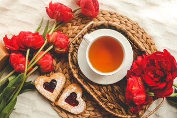 Tray with tasty breakfast, bouquet of peonies and gift for Valentine's Day on bed