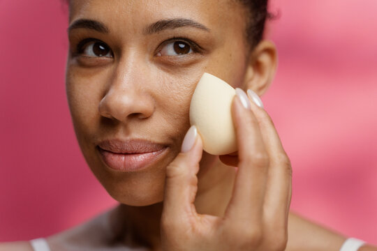 A woman uses a sponge while applying makeup