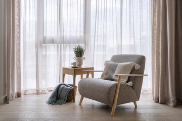 Grey armchair standing near coffee table with plaid in basket