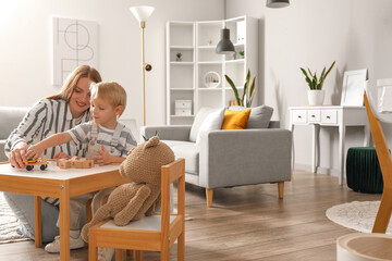 Mother and her little son playing with wooden toys at home