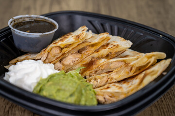 To go order of chicken quesadilla with sour cream and guacamole all packed in plastic container and dressing on the side