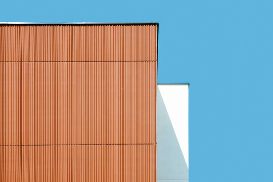 Fototapeta Architectural minimalism with brown building wall against blue sky